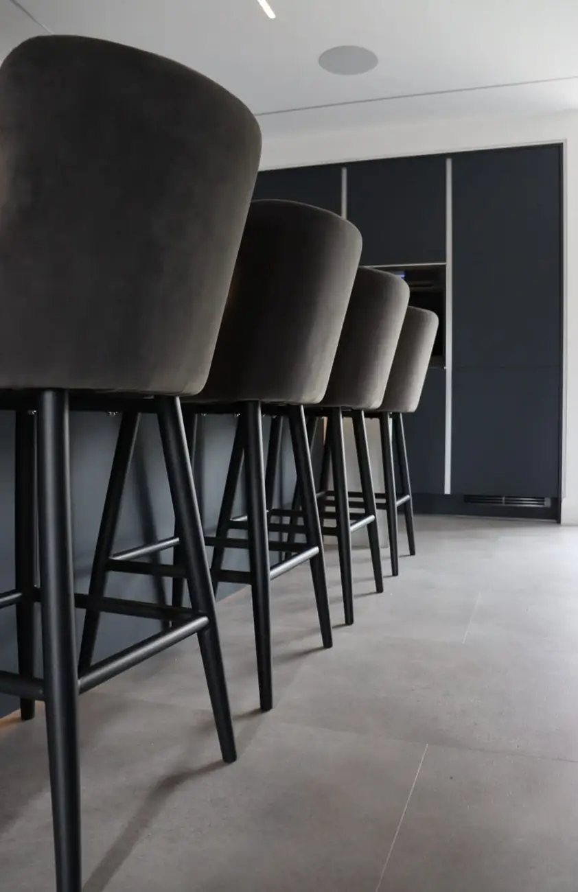 Row of velvet bar stools against handleless kitchen cabinetry